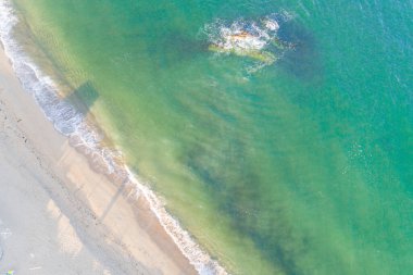 Güneş doğarken kumsalda turkuaz yeşil bir denizin dalgaları, İHA 'nın tam üstünde.