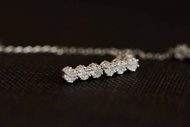 Koyu renk kumaş yüzeyde duran zarif elmas kolye.