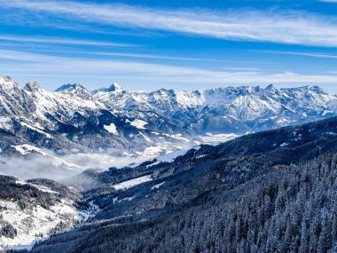 Kışın açık mavi gökyüzünün altında karlı dağlar.