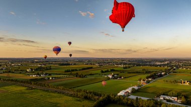 Şafak güzel bir şekilde ufukta beliriyor, sıcak hava balonları üzerine sıcak bir renk döküyor..