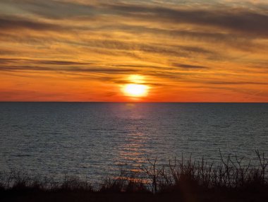 Dalgalar ve renkli bulutlarla okyanusun üzerinde gün batımı.
