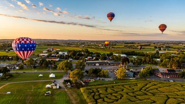 Balonlar zarif bir şekilde süzülür, sabah sisinin yumuşak, altın ışıklarıyla aydınlanır..