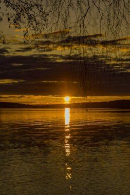 Gün batımı sakin su yüzeyine yansıyor