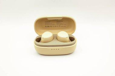 Kablosuz kulaklıklar beyaz bir yüzeydeki şarj kutusuna yerleştirilmiş..