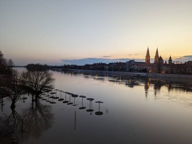 Gün batımında binaları olan bir nehrin manzarası.