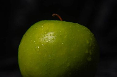 Koyu arkaplanda parlak yeşil elma