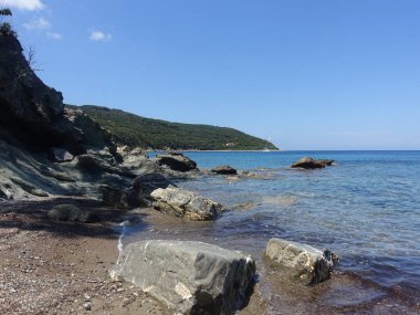 Açık mavi gökyüzünün altında Rocky plajı manzarası