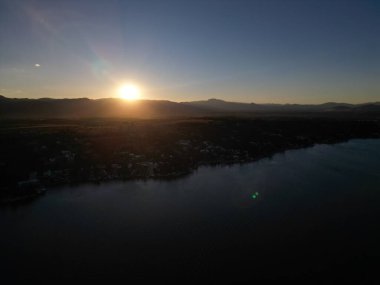 Sakin bir gölün üzerinde gün doğumu dağları yansıtıyor..