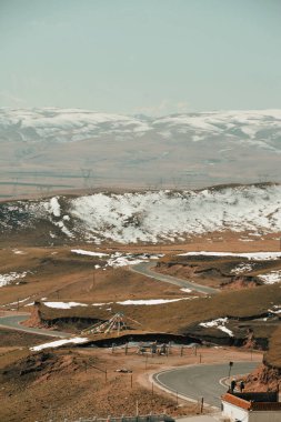 Dönek yola bakan karlı dağlar ve çimenli arazi