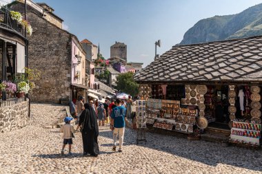 Mostar, Bosnia and Herzegovina, Aug. 2023. A lively group of people walking together down a picturesque cobblestone street in the historic city of Mostar.
