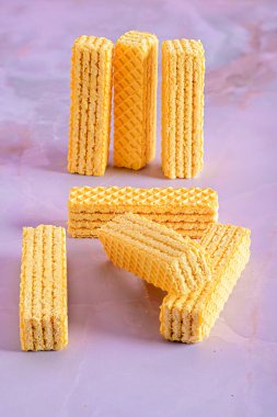 Yığılmış sarı gofretler mor yüzeyde sıralanmış.