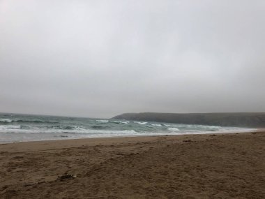 Hafif okyanus dalgalarıyla bulutlu sahil sahnesi