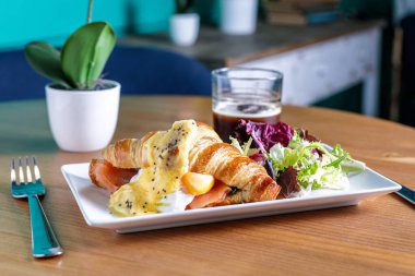 Salata ve içecekle servis edilen kruvasan tabağı.