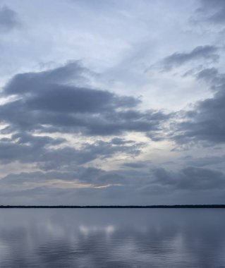 Sakin su bulutlu gökyüzünü yansıtıyor