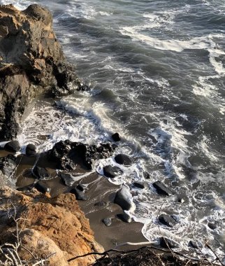 Dalgalar okyanus yakınlarındaki kayalık kıyılara çarpıyor.