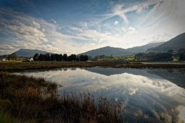 Dağları ve gökyüzünü yansıtan manzara