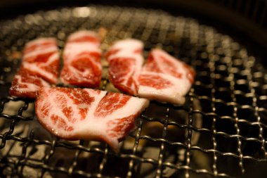Grilling marbled meat slices on barbecue