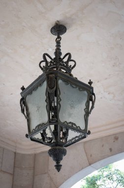 Tavandan sarkan eski ve süslü demir bir lambanın ayrıntıları. Kare şeklindedir ve Barcelona 'nın mimarisinden eski bir binadadır..