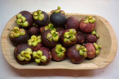 Tropik mangosenler ahşap kasede canlı mor renkler sergiliyorlar..