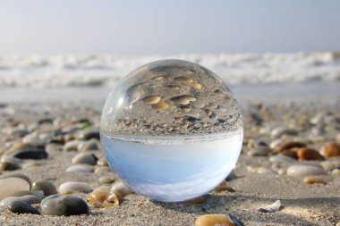 Plajı ve okyanusu yansıtan cam küre.