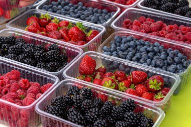 Plastik kaplarda çeşitli meyveler var.