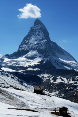 Kar kaplı dağ zirvesi berrak mavi gökyüzünün altında kendine özgü bir şekle sahip.