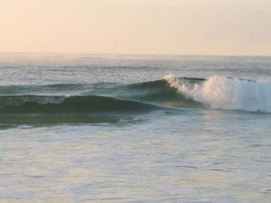 Gün batımında dalgalar yavaşça kıyıya vuruyor.