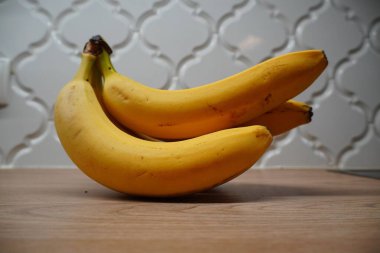 Mutfaktaki ahşap tezgahta duran bir avuç sarı muz..