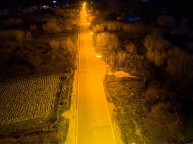 Gece sokak lambalarıyla aydınlatılmış boş bir yol.