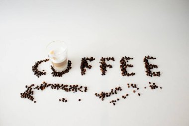 Kahve çekirdekleri kahveyi beyaz yüzeyde hecelemek için düzenlenmiştir.