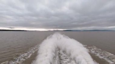 Bulutlu Gök Altında Geniş Göl Üzerinde Tekne Uyanışı ve Su Spreyi Görünümü