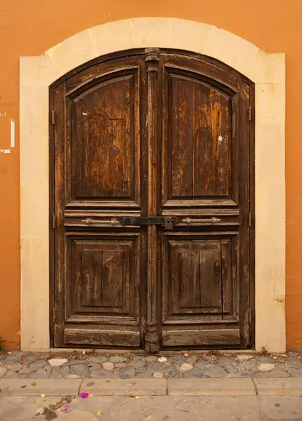 Turuncu arka planda kemer dizaynlı ahşap çift kapı.