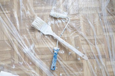 Ahşap zeminde paten, kazıyıcı ve plastik çarşaf da dahil olmak üzere boyama araçları