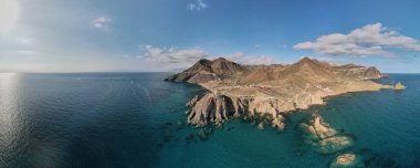 Dağları ve suyu olan kıyı manzarasının panoramik görüntüsü.