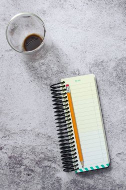 Not defteri kalem ve kahve fincanı gri yüzeyde.