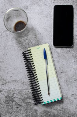 Gri yüzeydeki kalem akıllı telefon kahve fincanı.