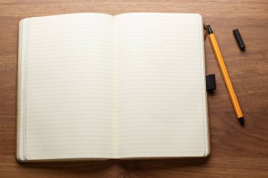 Ahşap masaya yerleştirilmiş boş defter kalemi