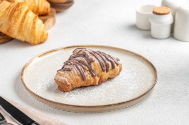 Beyaz tabakta çikolatalı kruvasan.