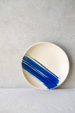 Yüzeyde mavi fırça darbesi tasarımı içeren seramik tabaka
