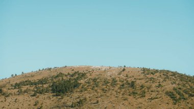 Açık mavi gökyüzünün altındaki kahverengi dağ manzarası
