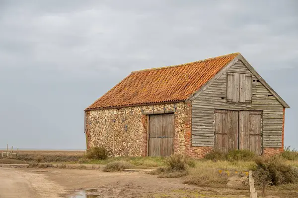 Kırsal alanda tek başına duran yıpranmış bir ahır.