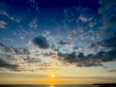 Gökyüzünde renkli bulutlarla okyanusun üzerinde gün batımı