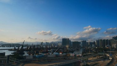 Parlak mavi gökyüzünün altında dağınık bulutlarla şehir manzarasının panoramik görüntüsü