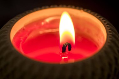 Kırmızı mum alevi, arka planda yavaşça parlıyor.