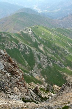 Kayalık arazisi ve uzak tepeleri olan yemyeşil dağları