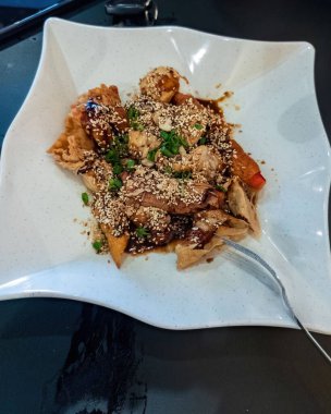 Koyu soslu ve susam tohumlu kızarmış Asya yemeği.