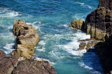 Dalgalar suyla kayalık kıyılara çarpıyor.