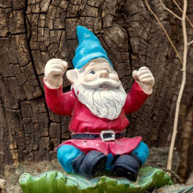 Ağaç kabuğuna karşı neşeli bahçe cücesi figürünün yakın çekimi