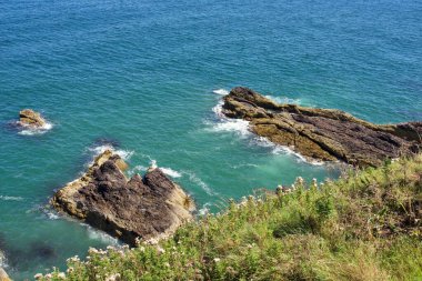 Açık mavi okyanus sularına ve dalgalara bakan kayalık kıyı şeridi