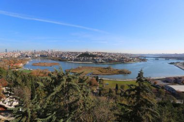 Nehir ve yemyeşil gökyüzü altında panoramik şehir manzarası